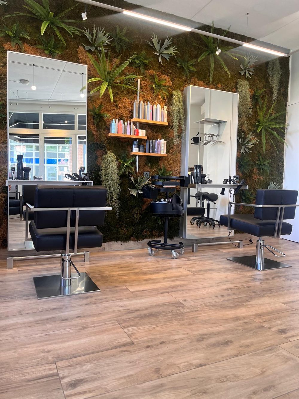 De salon van hoofdzaken, met de groene moswand en de werkplekken.
